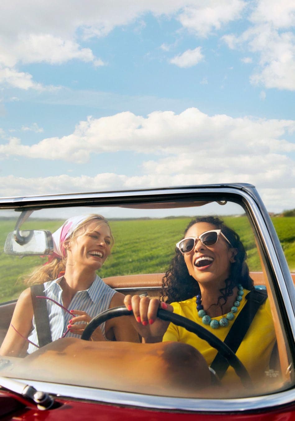 Two women laughing in an open-top car