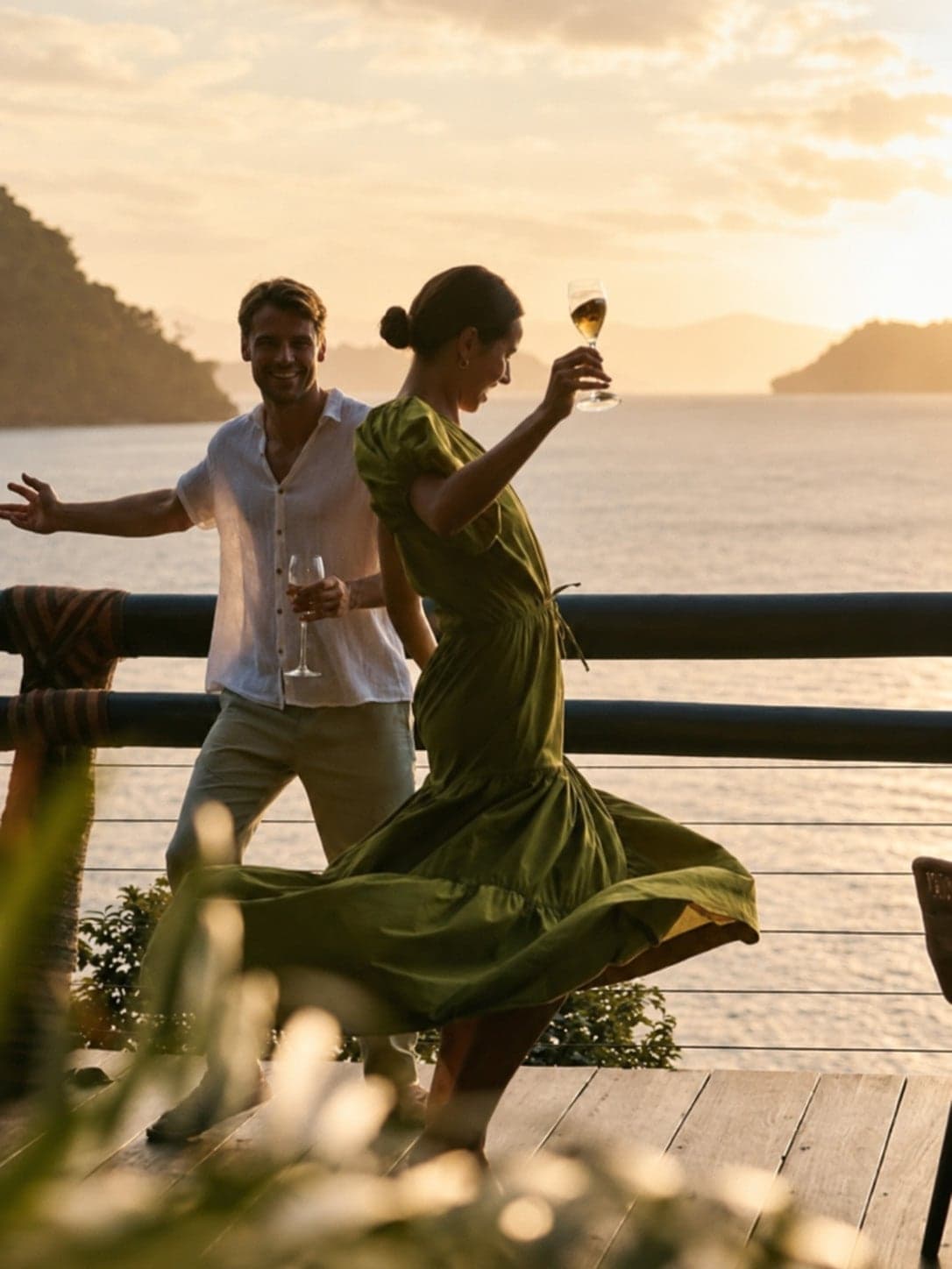 A couple dancing on a lakeside deck at sunset